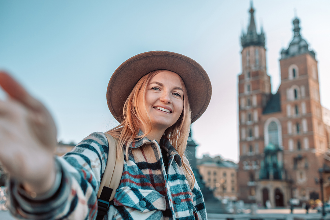 A traveler enjoying Krakow’s main square with St. Mary’s Basilica rising behind her, capturing the city’s youthful vibe.