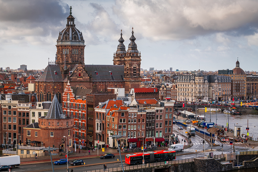 A panoramic view of Amsterdam with its churches and winding canals defining the historic skyline.