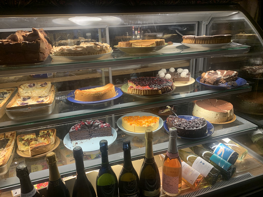 A rich display of cakes and pastries in a Tallinn dessert shop, known for homemade treats and freshly roasted coffee.